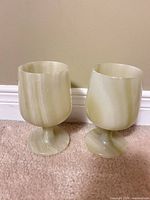 Front view of both pale green onyx goblets standing on carpet