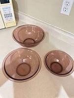 Three cranberry glass bowls nested together