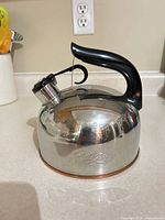 Full view of kettle showing overall form, handle, whistle, and copper bottom