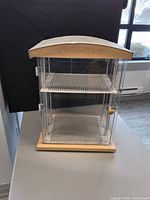 Front view showing acrylic sides, hinged door, shelf, wood base