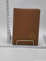 Closed brown hardcover stamp album between rulers
