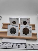 All four coins in 2×2 holders with handwritten country and year labels