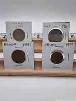 Front view of four coins in flips, ruler for scale