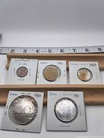 All five coins in holders with ruler for scale