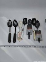 All seven utensils arranged with ruler for scale