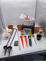 Full lot overview showing planters, stakes, lanterns, tools and accessories