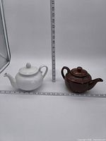 both teapots side by side with measuring rulers