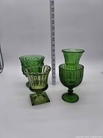 Group shot of four green glass vases with ruler for scale