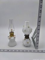 Both miniature oil lamps with ruler for scale