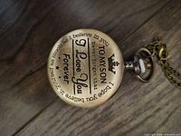 Front cover of brass-tone pocket watch showing full inscription and attached chain
