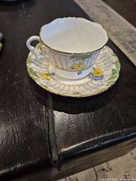 Angled view of teacup on saucer showing floral design and gold trim
