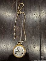 Front view showing dial, numerals, hands and attached chain