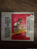 Front view of red O-Pee-Chee baseball card wax pack wrapper showing catcher illustration and bilingual text