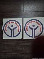 Two identical Scotia Hockey College iron-on decals on a dark floor