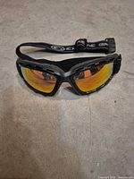 Front view of goggles showing mirrored lens, frame, and branded strap