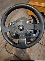 Front view of Thrustmaster TMX steering wheel showing buttons, paddle shifters and branding