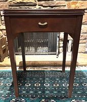 Front view of wood sewing machine cabinet showing drawer pull, legs and overall condition