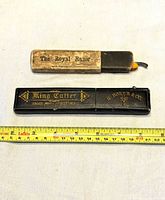 Two closed razor boxes beside measuring tape for scale