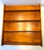 Front view of the wooden wall rack showing four shelves and mounting holes