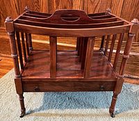 front view of mahogany Canterbury showing dividers, drawer, and casters