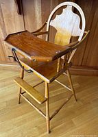 Front angled view showing full high chair, tray raised, leather strap visible