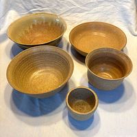 Five stoneware bowls displayed to show size gradient and glaze colors