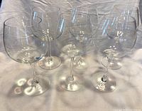 Six clear balloon bowl wine glasses arranged on white background