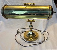 Front view of brass bankers lamp showing cylindrical shade, base, and cord