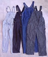 Four pairs of overalls in light denim, black corduroy, blue denim and grey twill laid flat