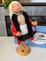 Full view of Woman in Red doll on wooden stand