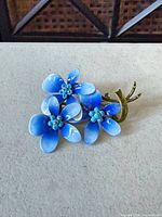 front view showing three blue enamel flowers and gold-tone stem