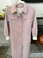 Full front view of mauve trench coat on hanger