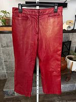 Front view of red leather cropped straight-leg pants on hanger