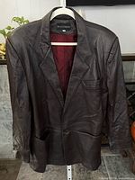 Full front view of brown leather blazer on hanger
