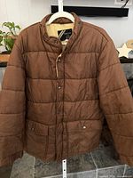 Full front view of brown quilted jacket on hanger