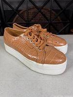 Three-quarter view of both sneakers showing uppers, laces, and platform soles