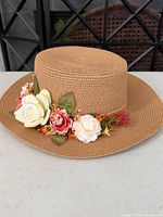 Front view showing floral trim on tan paper straw sun hat