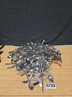 Pile of mixed stainless steel flatware on table