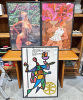 Three framed posters on table: Jamaica, abstract pink-orange, Pan American Games