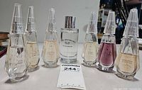 Group shot of six Beekman 1802 eau de toilette bottles and one Rose Apothecary eau de parfum bottle showing fill levels and labels