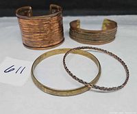 Front view of four bracelets showing designs and metals