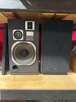 Front view of both Kenwood JL-730W speakers, one with grille removed showing drivers