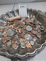 Bowl containing loose mixed U.S. coins with one sealed nickel roll