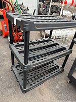 Overall view of black plastic three-tier shelving unit