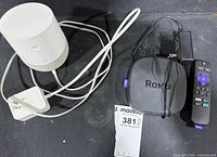 Google Home speaker, Roku player, Roku remote and power adapter on surface