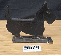 Full view of cast iron Scottie dog boot scraper on wood surface