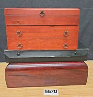 Stacked view showing three wooden flatware chests: Reed & Barton two-drawer, black chest, curved-lid chest