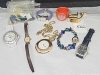 Overview of 8 watches and bag of band parts laid out