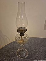 Full view of clear glass oil lamp with chimney