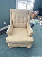 Front view of sand-coloured armchair showing button-tufted back, seat and skirt